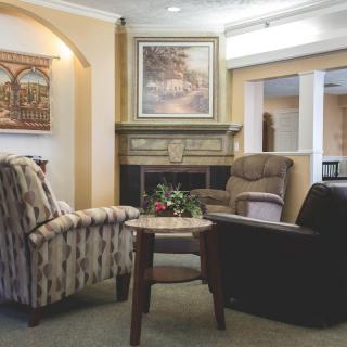 A cozy seating area featuring armchairs around a coffee table, with a fireplace and artwork in the background.