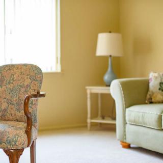 A cozy living room with a sofa, lamp, and floral chair by the window.