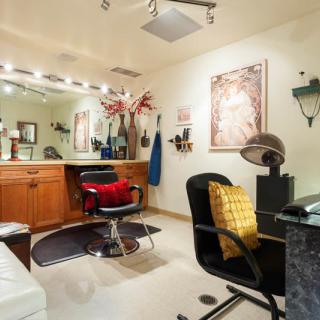 A stylish hair salon interior with well-arranged furniture and a large mirror reflecting the workspace.