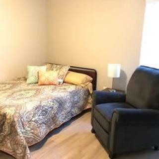 A cozy bedroom with a bed, armchair, and lamp.