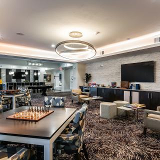 A modern lounge area with comfortable seating, a chess board, and a large television.