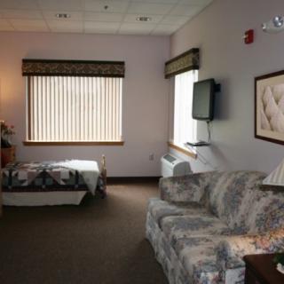A cozy hotel room with a bed, sofa, and wall-mounted television.