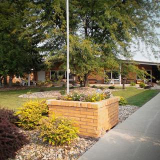 A building surrounded by a landscaped garden with a sidewalk and trees.