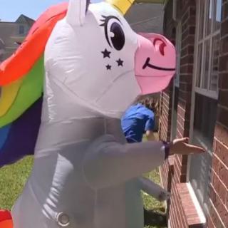 A person in an inflatable unicorn costume playfully knocking on a door.