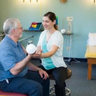 A physical therapist assists an elderly patient with rehabilitation exercises.