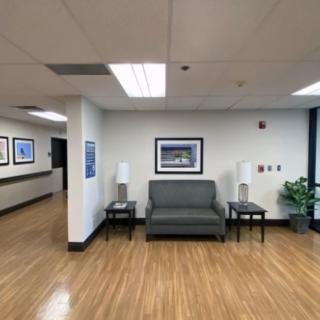 A waiting area with a sofa, two side tables with lamps, and artwork on the walls in an office setting.