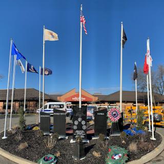 A serene memorial site featuring multiple flags, honoring veterans under a clear blue sky.