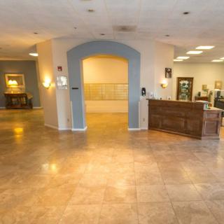 A spacious lobby area featuring a reception desk and an archway, with tile flooring and ambient lighting.