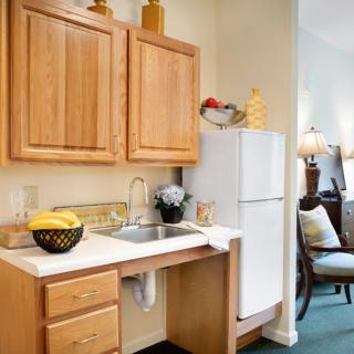 A compact kitchen area with wooden cabinets, a sink, and a refrigerator.