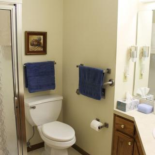 A neatly organized bathroom with blue towels and a framed picture.