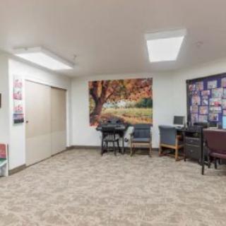 A small office waiting area with chairs, a computer, and decorative artwork on the walls.