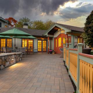 A charming patio at a restaurant during evening hours, illuminated by warm lights under a cloudy sky.