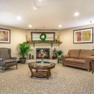 A cozy living room with a sofa, armchair, and coffee table centered around a decorated fireplace.