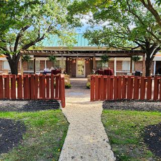A welcoming entrance to a charming building surrounded by lush trees and decorative landscaping.