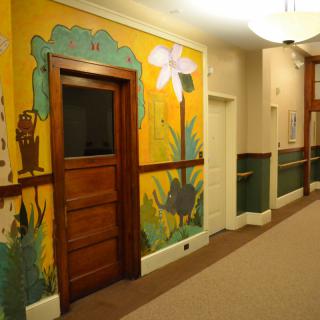 A hallway featuring a colorful mural with a wooden door and decorative elements.