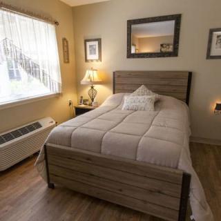 A cozy bedroom with a comfortable bed, lamp, and window creating a warm atmosphere.