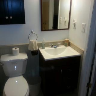 A small bathroom with a toilet, sink, and mirror.