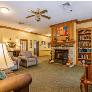 A cozy living room featuring a central fireplace, comfortable sofas, and surrounding bookshelves.