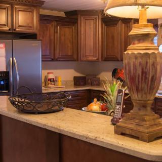 A cozy kitchen setting featuring wooden cabinets and a well-lit countertop with decorative items.