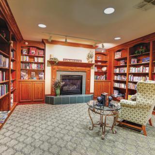 A cozy library corner with bookshelves, a fireplace, and a comfortable armchair, perfect for reading.