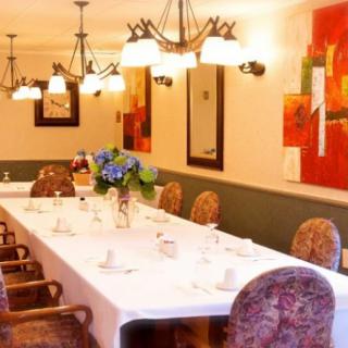 Elegant dining room with a long table, ornate chairs, and vibrant artwork on the walls.