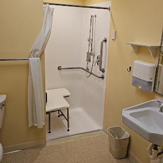 An accessible bathroom equipped with a shower, toilet, and sink.