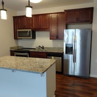 A modern kitchen featuring granite countertops, wooden cabinets, and stainless steel appliances.