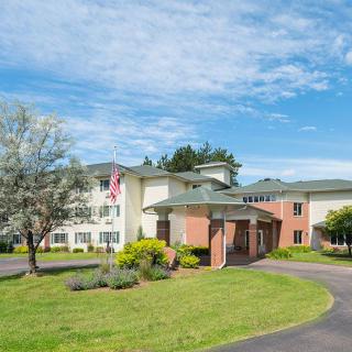 A picturesque building with a well-maintained landscape and a circular driveway under a clear blue sky.
