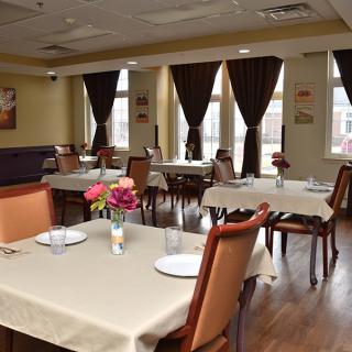 A cozy restaurant dining area with neatly arranged tables and chairs, adorned with flowers.