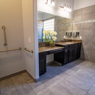 Modern bathroom with a sleek vanity and large mirror, featuring clean tile flooring and contemporary lighting.