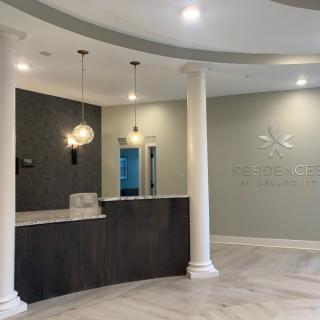 A modern reception area with sleek design elements, featuring a curved desk, elegant lighting, and classic columns.