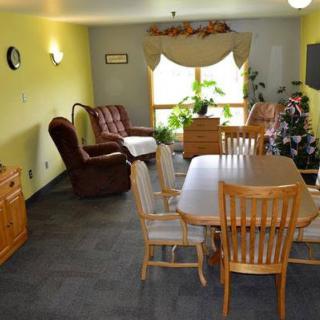 A cozy living and dining area with wooden furniture and indoor plants.