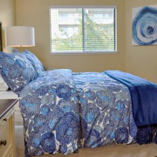 A cozy bedroom with blue-patterned bedding, a window view, and matching decor.