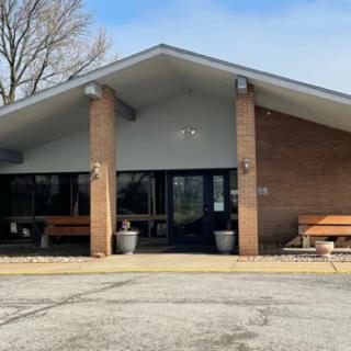 A single-story building with a sloped roof and brick exterior, featuring benches near the entrance.