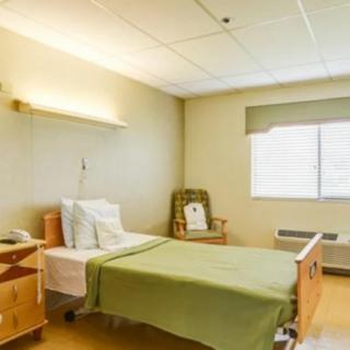 A clean, empty hospital room with a single bed and basic furnishings.