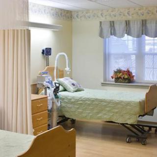 A hospital room with a bed, medical equipment, and a flower arrangement on the windowsill.