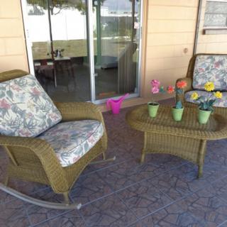 A cozy outdoor patio setup with wicker chairs and a table decorated with colorful potted plants.