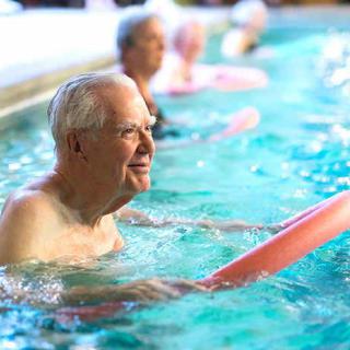 Elderly individuals participating in a water aerobics class in a swimming pool.