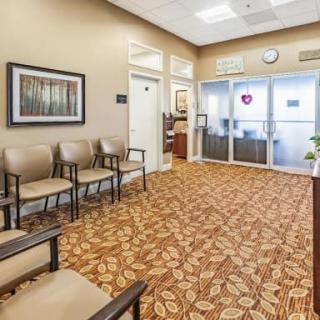 An empty waiting room with chairs, decorated carpet, and wall artwork.
