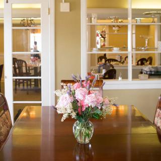 A cozy dining room with a wooden table adorned with a vase of flowers.