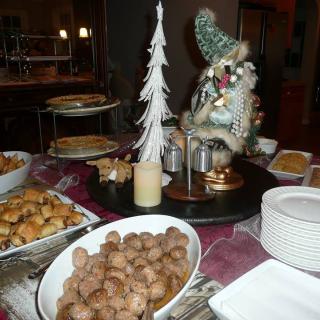 A festive dining table set for Christmas with a variety of foods and seasonal decorations.