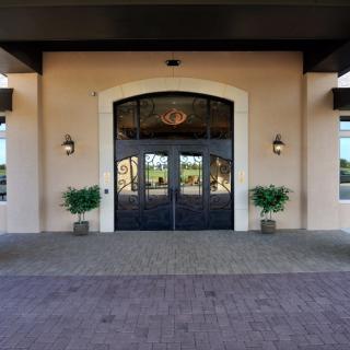A symmetrical building entrance with double doors and potted plants on either side.