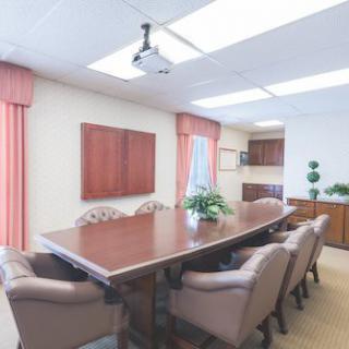 A well-lit conference room with a long meeting table and comfortable chairs.