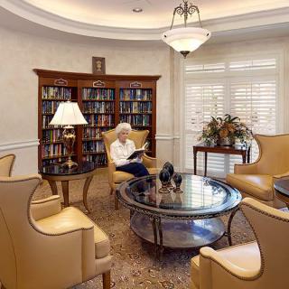 A cozy library with an elderly person reading in a comfortable seating area.