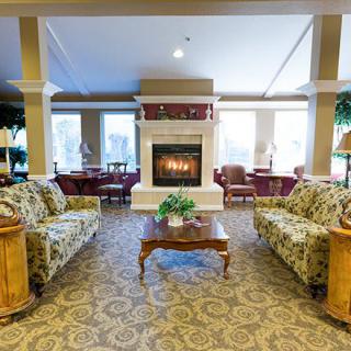 A cozy living room with a central fireplace, surrounded by patterned sofas and wooden furniture.