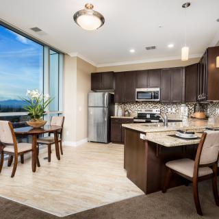 A modern apartment kitchen and dining area with elegant furnishings and a large window providing natural light.