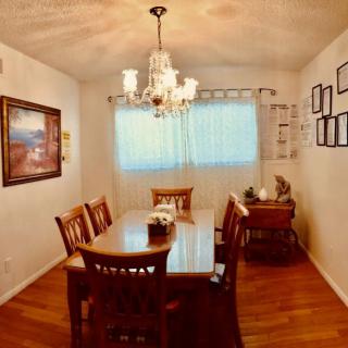 A cozy dining room featuring a wooden table set, elegant chandelier, and tasteful artwork on the walls.
