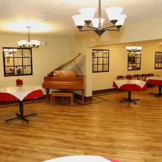 An elegant dining area with a grand piano and beautifully set tables.