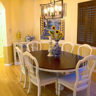 A cozy dining room with a round table, elegant white chairs, and a vase of sunflowers as the centerpiece.