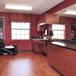 An empty barber shop with red walls, mirrors, and cabinets.